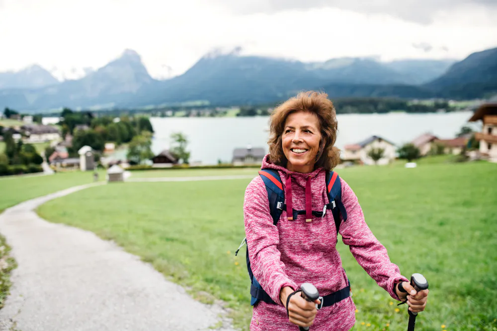 senior woman with walking poles hiking in nature
