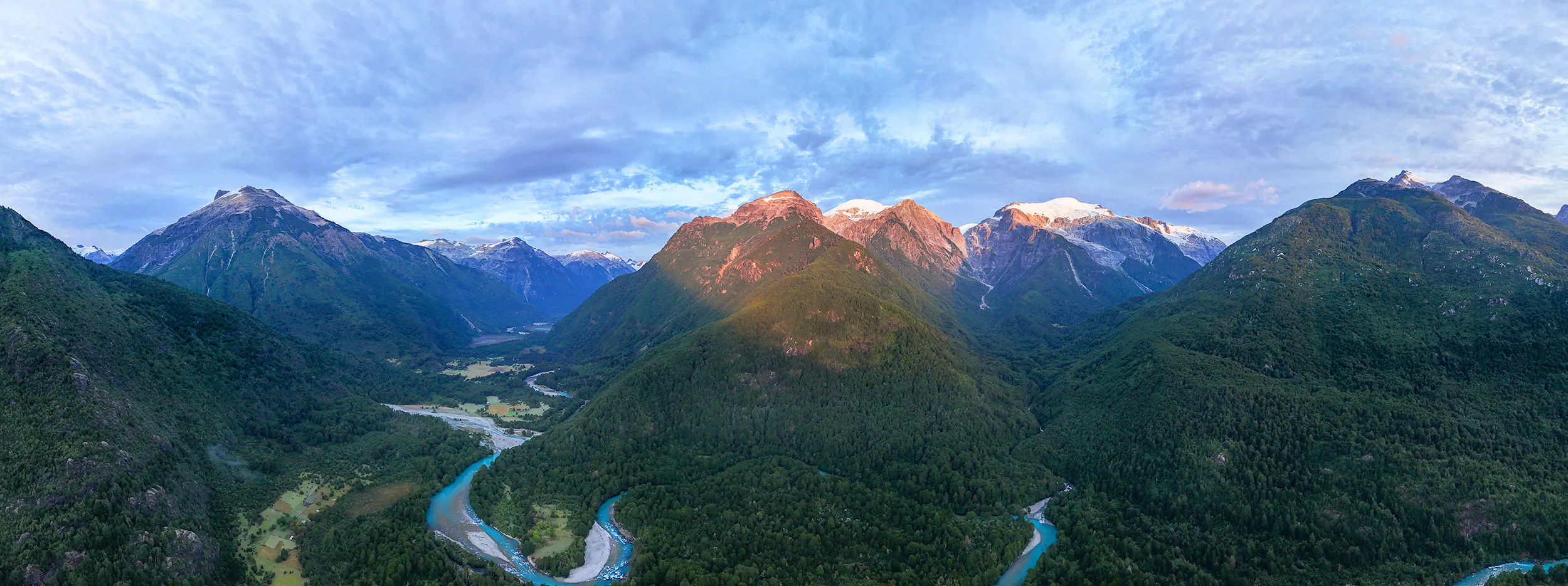 View of Cochamo Valley at sunset with turquoise, glacier-fed rivers, glaciated peaks, and deep forests.