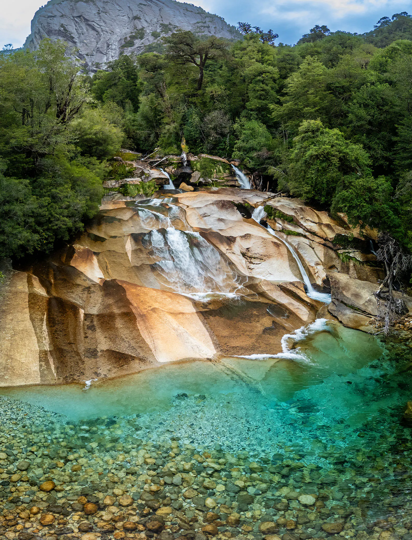 Gorgeous turquoise, glacial-fed water flowing over smooth granite into an idyllic pool in Cochamo Valley, Patagonia