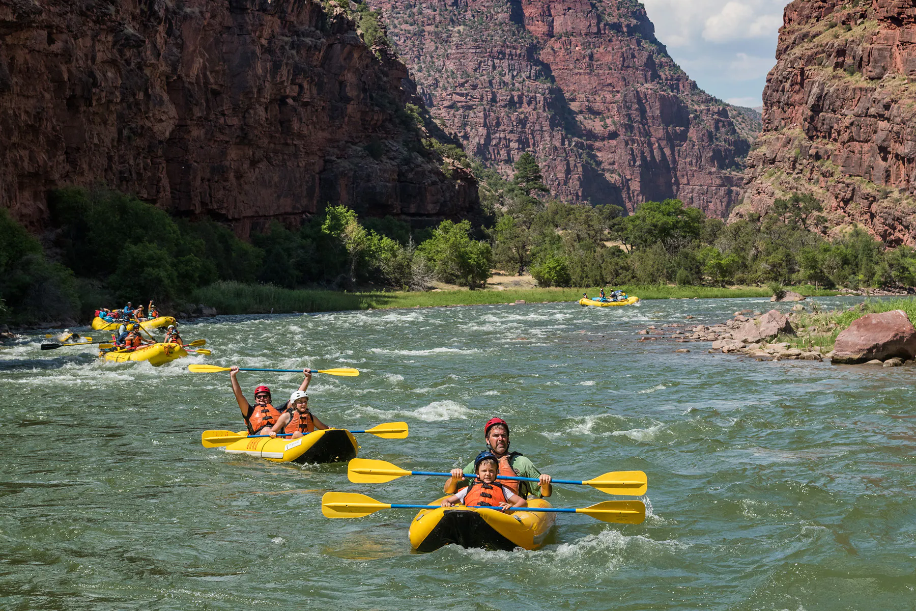 OARS guests on inflatable kayaks and rafts in mild rapids on the Green River - Gates of Lodore Rafting Trip in Dinosaur National Monument