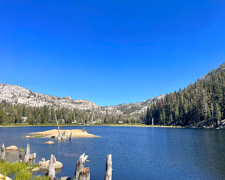 Gorgeous mountain lake surrounded by conifers and granite outcroppings in the SIerra Nevada