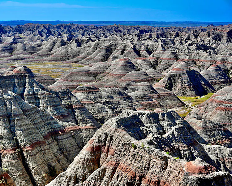 Badlands of South Dakota, striated and colorful mounds with blue sky