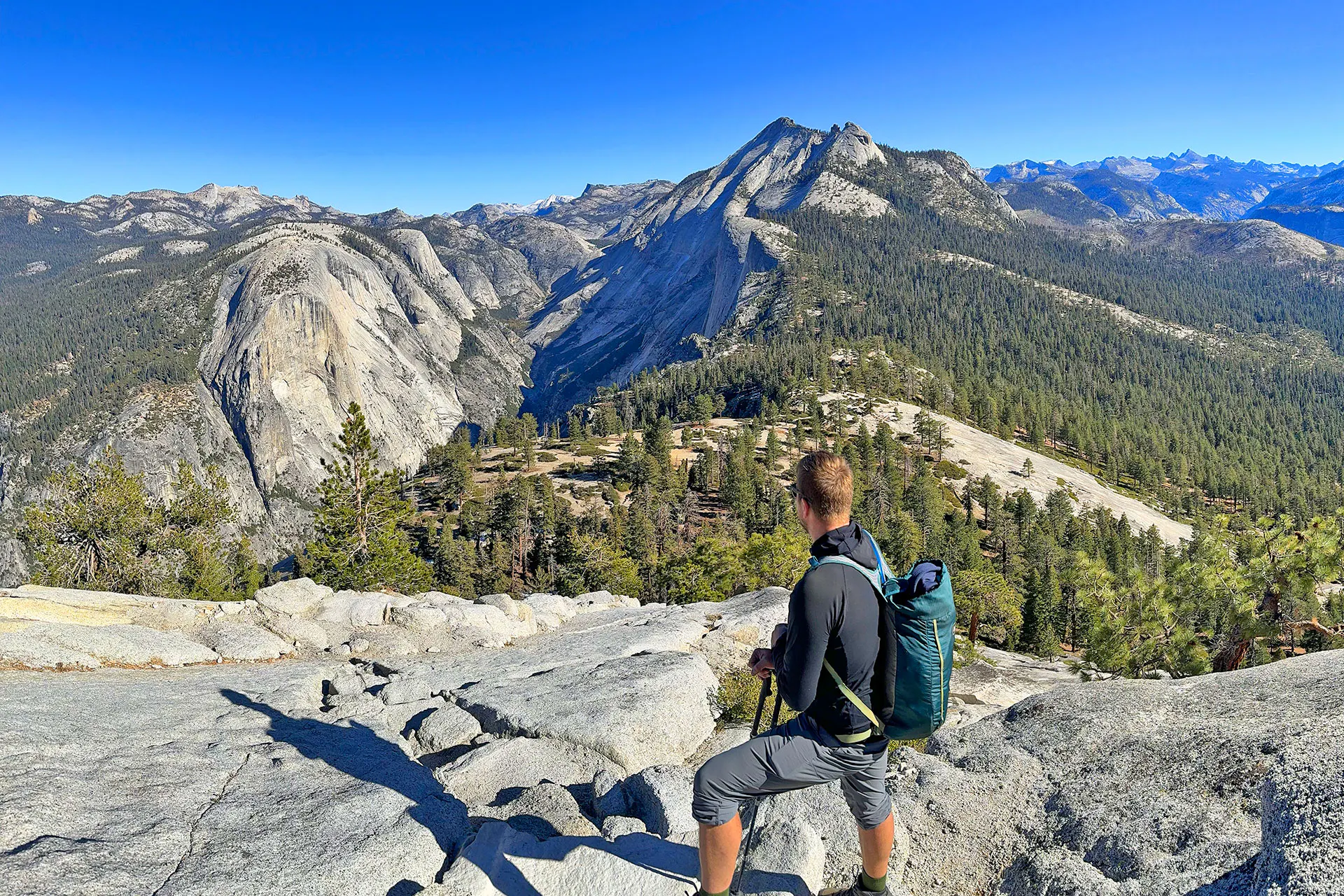 Male hiker standing on the top of Subdome in Yosemite National Park looking up at the high country on a beautiful, sunny day.