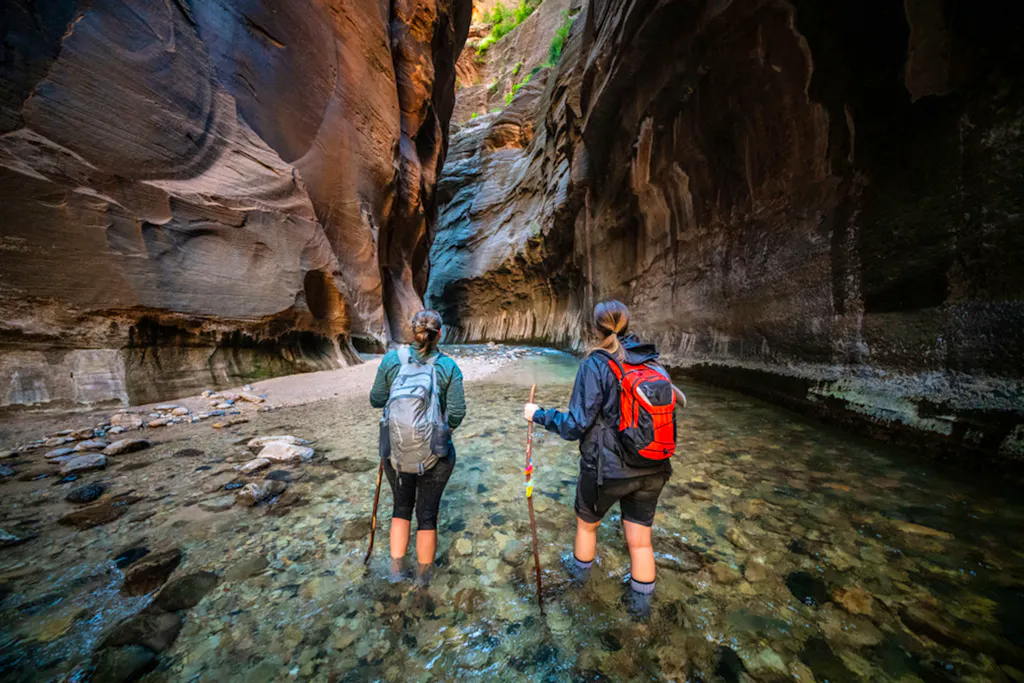 female hikers going through the narrows at zion national park