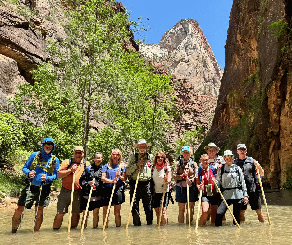 group trekking the narrows with poles in zion