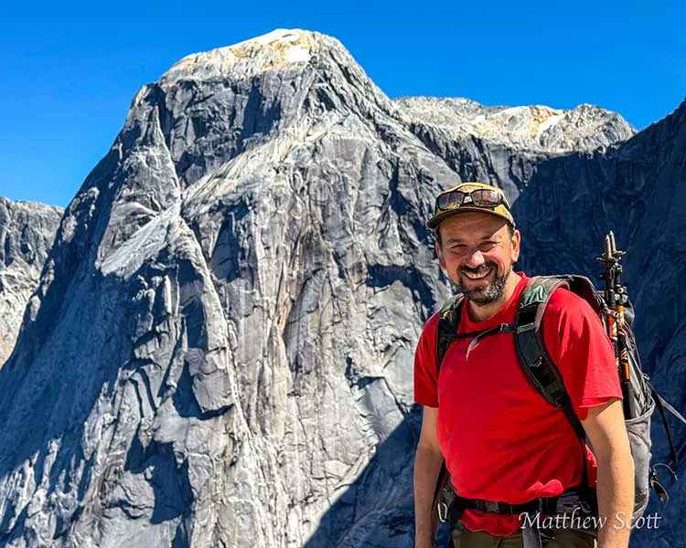 Rodrigo Condeza, founder of Puelo Patagonia standing in a red hiking shirt in front of giant granite cliffs in Cochamo Valley