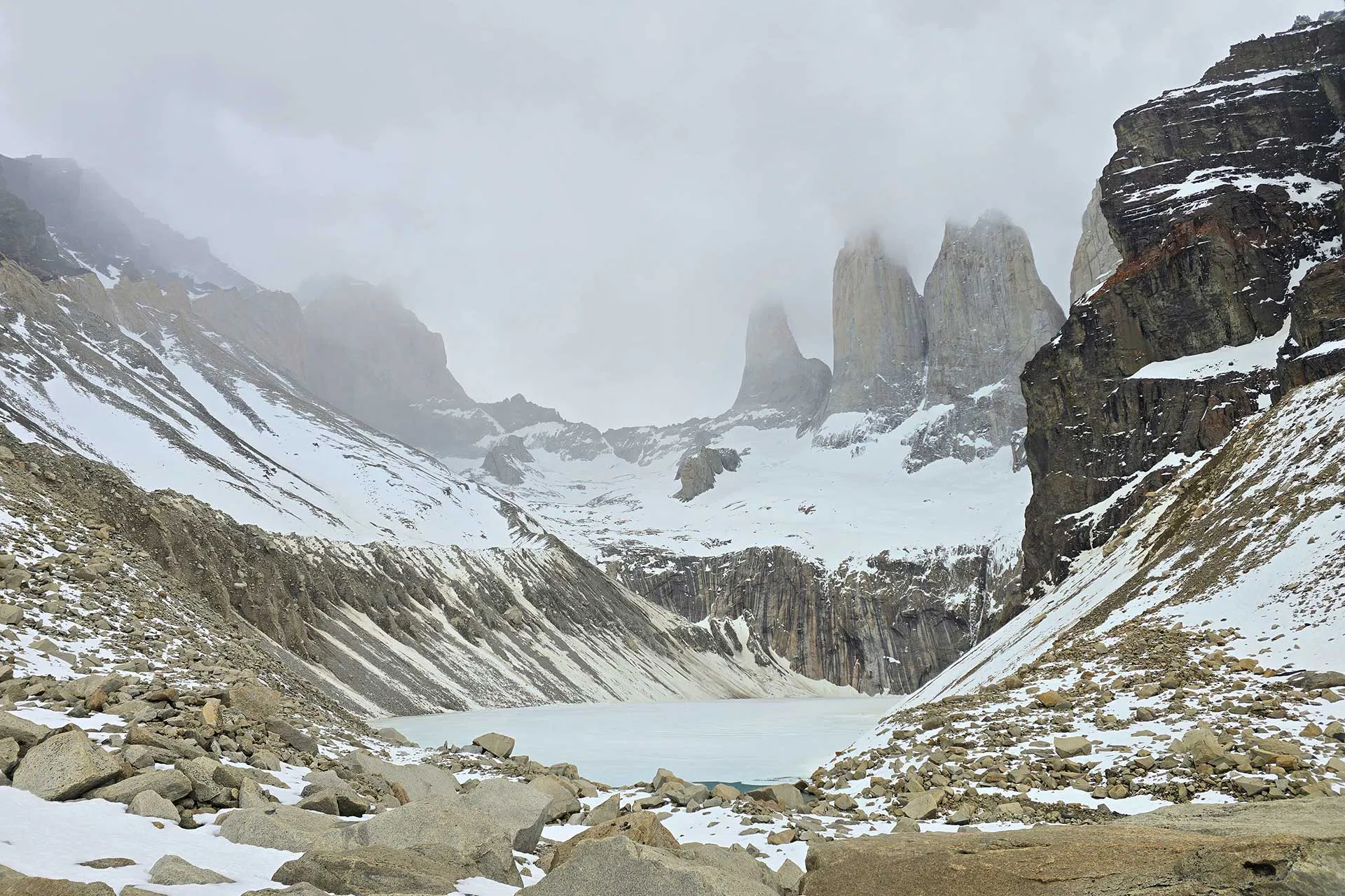 Torres del Paine granite towers with a frozen alpine lake and snowy slopes