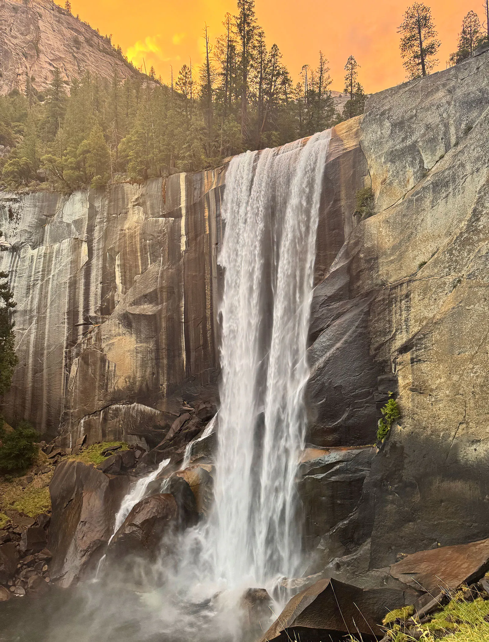 Vernal Fall in Yosemite National Park at sunset, with yellow clouds framing the waterfall