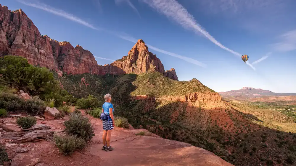 female standing at peak of watchman trail in zion national park