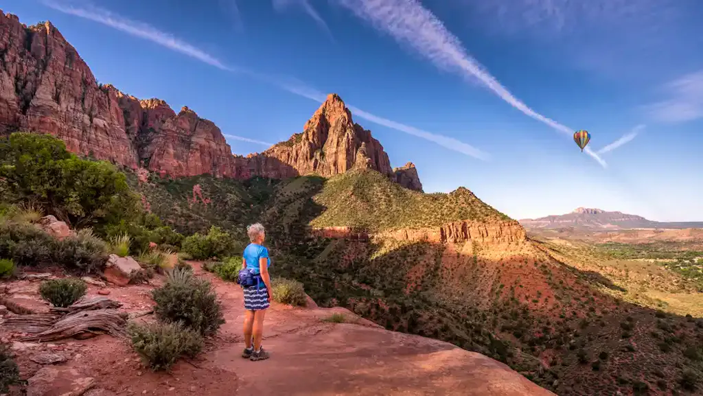 female standing at peak of watchman trail in zion national park