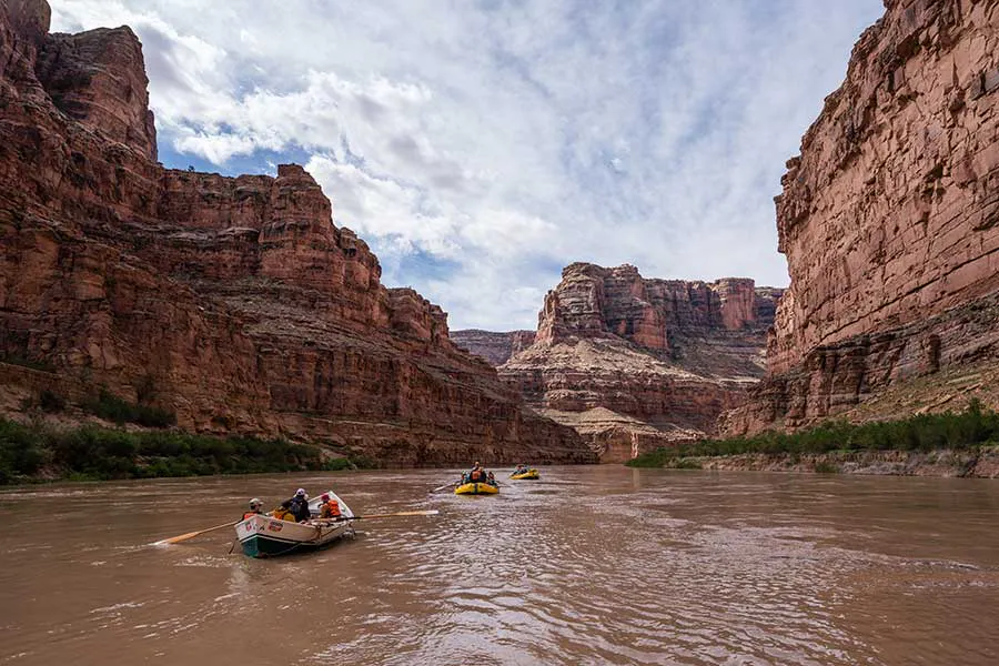 An OARS dory and 2 rafts floating through Meander Canyon on the Colorado River in Cataract Canyon, Utah
