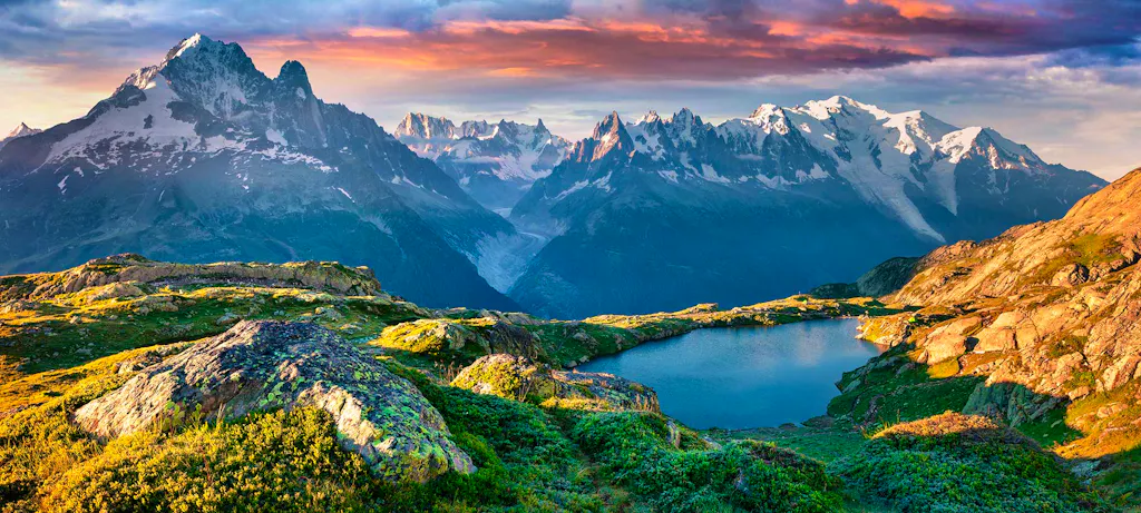 Stunning sunset with pink clouds, alpine peaks and a crystal clear lake in the Alps on the Tour du Mont Blanc