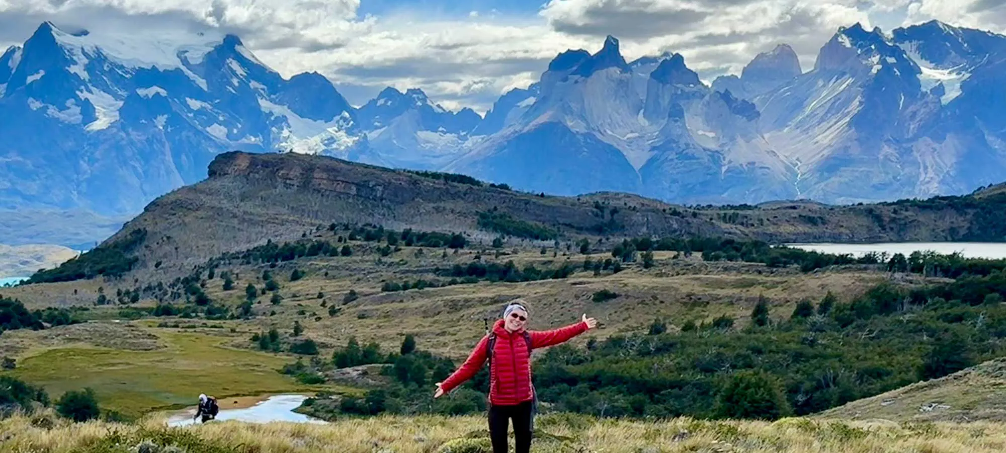 Woman standing in front of the jagged horn-shaped peaks of Torres del Paine while hiking the O Circuit, Patagonia